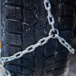 Vodič kontrolujúci staré snehové reťaze, pričom ukazuje na poškodené a zhrdzavené ohnivko.